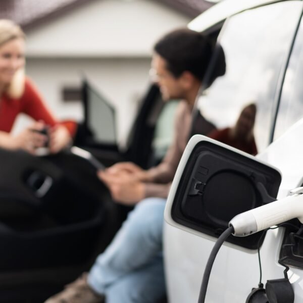 Electric Car Being Charged While Two People Have A Conversation, Representing Sustainable Energy And Modern Transportation